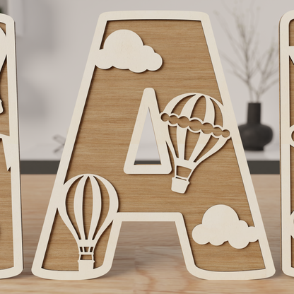 zoom sur une lettre en bois naturelle décorée de montgolfières et nuages, idée cadeau naissance | close-up houten letter naturel met luchtballon en wolken, gepersonaliseerd kraamcadeau